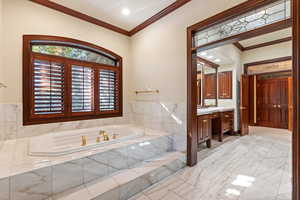 Bathroom with vanity, ornamental molding, and tiled tub