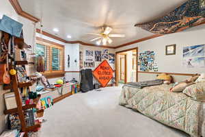 Carpeted bedroom with ceiling fan, crown molding, a textured ceiling, and ensuite bathroom