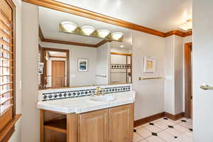 Bathroom with vanity, ornamental molding, tasteful backsplash, and a textured ceiling