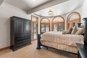 Bedroom featuring light carpet and beam ceiling