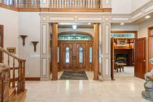 Foyer entrance with ornamental molding, ornate columns, and a towering ceiling