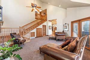 Living room featuring ceiling fan, high vaulted ceiling, and light colored carpet