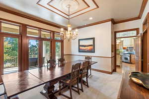 Dining space with crown molding, a chandelier, and light colored carpet