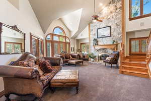 Living room with a healthy amount of sunlight, carpet flooring, and high vaulted ceiling