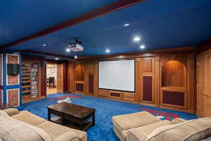 Home theater with carpet floors and beamed ceiling