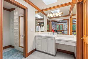 Bathroom with vanity, crown molding, a shower with shower door, and a skylight