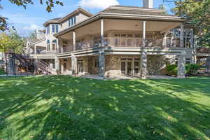 Back of property with a yard, a patio area, and a balcony