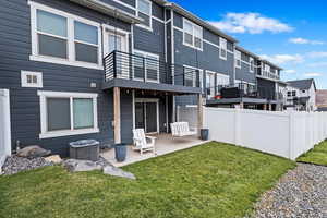 Rear view of property featuring central AC, a patio area, and a lawn