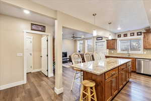 Kitchen featuring stainless steel dishwasher, hardwood / wood-style floors, a textured ceiling, a breakfast bar area, and a kitchen island