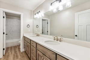 Full bathroom featuring washtub / shower combination, vanity, wood-type flooring, and toilet