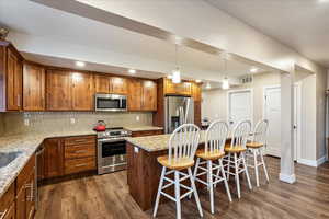 Kitchen with tasteful backsplash, dark wood-type flooring, and appliances with stainless steel finishes