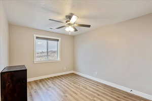 Unfurnished room with ceiling fan, a textured ceiling, and light wood-type flooring