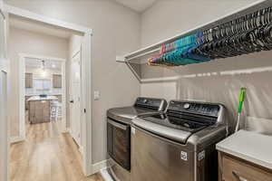 Washroom with washer and clothes dryer and light hardwood / wood-style flooring