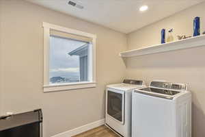 Clothes washing area featuring light hardwood / wood-style flooring and washing machine and clothes dryer