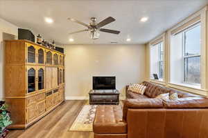 Living room featuring a textured ceiling, hardwood / wood-style flooring, and ceiling fan