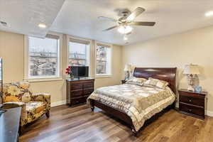 Bedroom with hardwood / wood-style floors, a textured ceiling, and ceiling fan