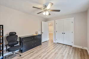 Office space featuring ceiling fan, a textured ceiling, and light wood-type flooring