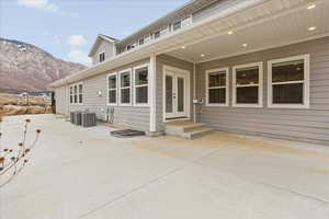 Back of property featuring a mountain view, central air condition unit, a patio, and french doors