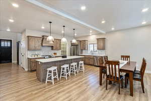 Kitchen featuring hanging light fixtures, a kitchen island, stainless steel appliances, and light hardwood / wood-style floors