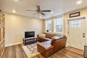 Living room with ceiling fan, wood-type flooring, and a textured ceiling