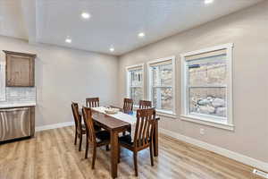 Dining room with light hardwood / wood-style floors and a textured ceiling