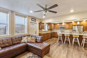 Living room featuring a textured ceiling, light wood-type flooring, ceiling fan, and sink