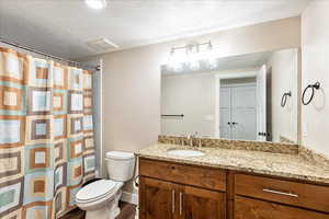 Bathroom featuring wood-type flooring, vanity, a textured ceiling, and toilet