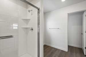 Bathroom featuring hardwood / wood-style floors and a shower with shower door