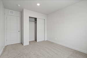 Unfurnished bedroom with light carpet and a closet