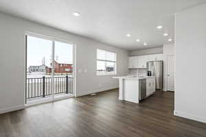 Kitchen with sink, stainless steel appliances, dark hardwood / wood-style flooring, a center island with sink, and white cabinets