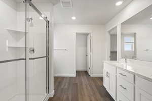 Bathroom with hardwood / wood-style floors, vanity, and a shower with shower door