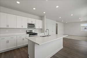 Kitchen featuring sink, dark hardwood / wood-style flooring, a kitchen island with sink, white cabinets, and appliances with stainless steel finishes