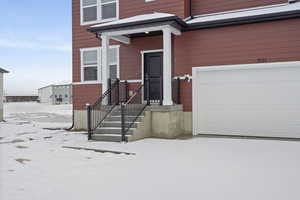 Snow covered property entrance featuring a garage