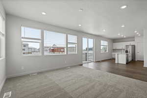 Unfurnished living room featuring dark carpet and a textured ceiling