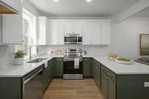 *Model Home Photo. Kitchen with white cabinets, sink, and stainless steel appliances