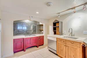 Kitchen featuring decorative backsplash, white dishwasher, tile counters, and sink