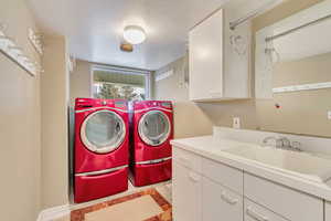 Washroom with separate washer and dryer, sink, cabinets, and a textured ceiling