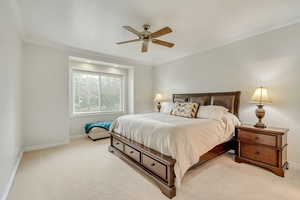 Bedroom with light carpet, ceiling fan, and ornamental molding