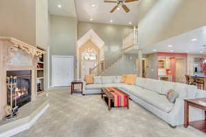 Living room featuring light carpet, built in features, a towering ceiling, and ceiling fan