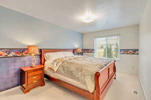 Bedroom with light carpet and a textured ceiling