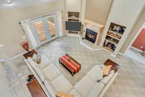 Carpeted living room featuring a premium fireplace, built in features, high vaulted ceiling, and french doors