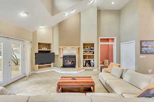 Living room with built in shelves, french doors, high vaulted ceiling, and light colored carpet