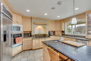 Kitchen with a kitchen breakfast bar, built in appliances, decorative light fixtures, and sink