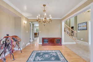 Interior space featuring light hardwood / wood-style floors, crown molding, and a chandelier