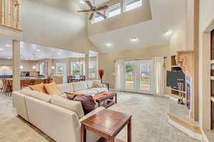 Living room with light colored carpet, high vaulted ceiling, and ceiling fan