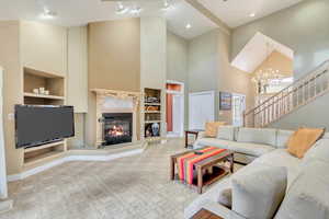 Carpeted living room featuring built in shelves, a towering ceiling, and a notable chandelier