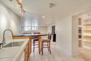 Kitchen with oven, sink, rail lighting, light tile patterned floors, and a textured ceiling