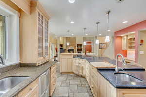 Kitchen with dark stone counters, sink, a center island, and hanging light fixtures