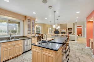 Kitchen with a kitchen island with sink, sink, ceiling fan, and pendant lighting