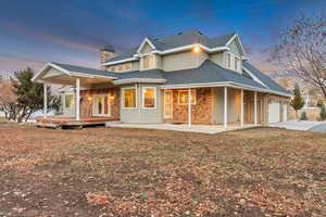 Back house at dusk with a wooden deck and a garage